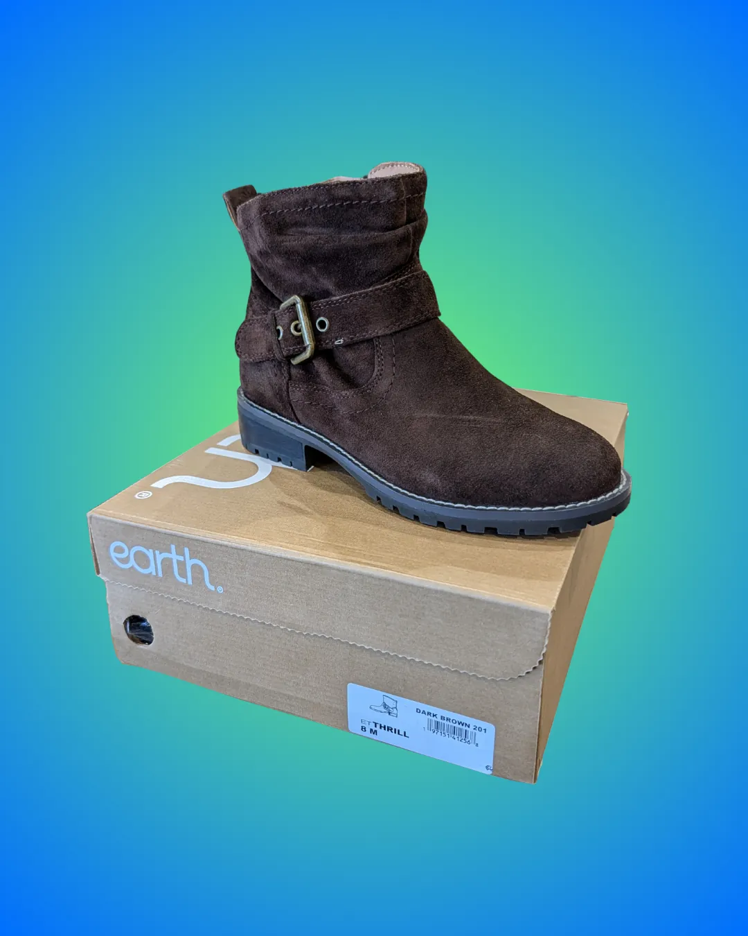 Earth Thrill ankle boot in dark brown suede with a buckled ankle strap and a chunky lug sole, sitting on its tan Earth shoebox